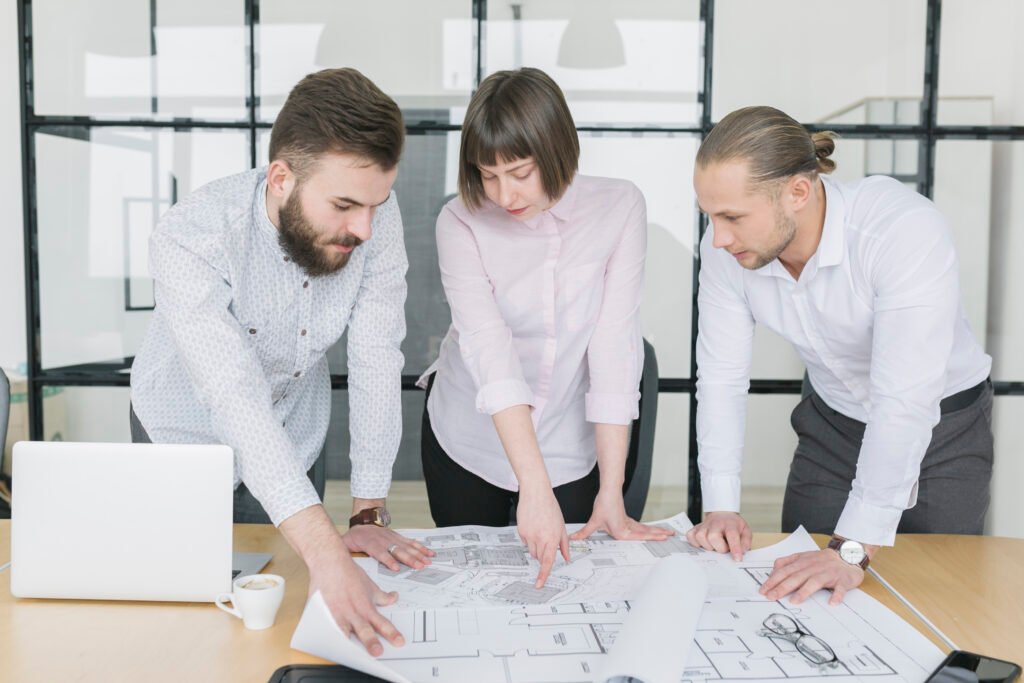 Business professionals reviewing architectural plans in an office, representing our team and values