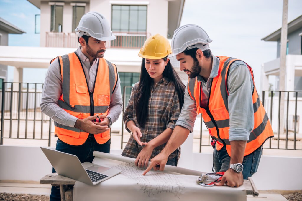 Civil engineer, construction worker, and architects wearing hardhats and safety vests working together at a construction site