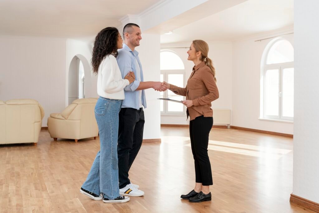Female real estate agent shaking hands with a couple inside their new home