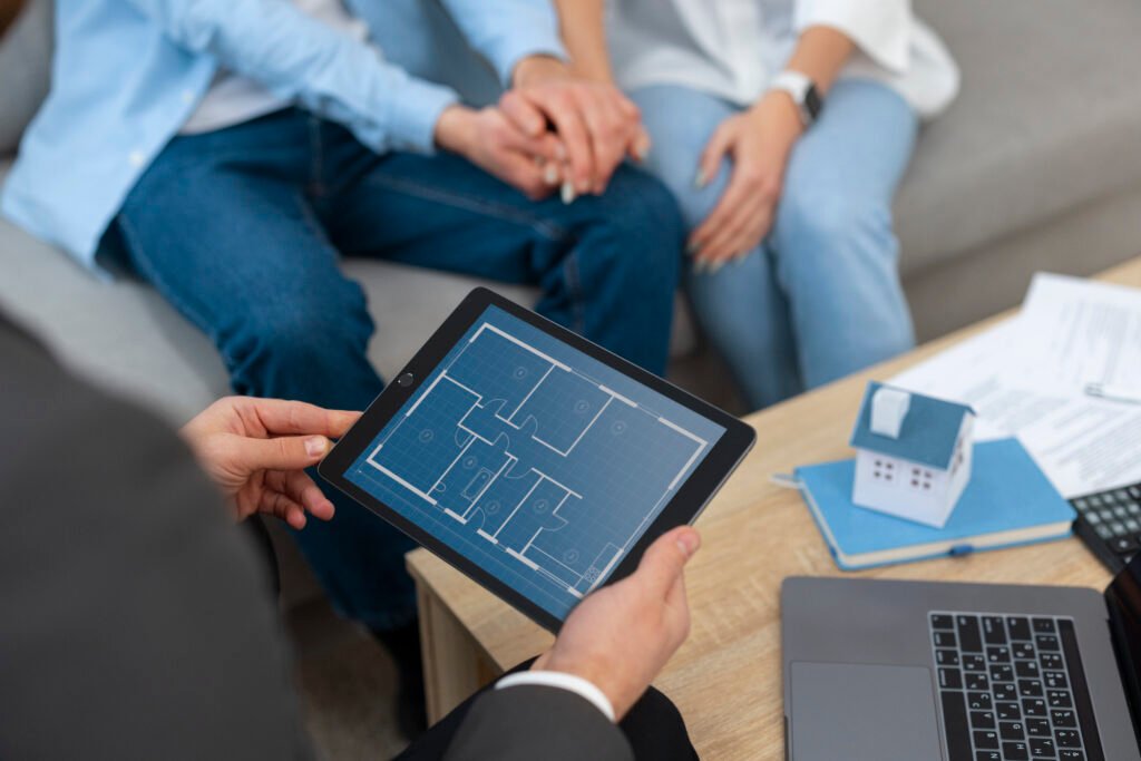 Male real estate agent showing house to a couple, holding a tablet displaying a floor plan
